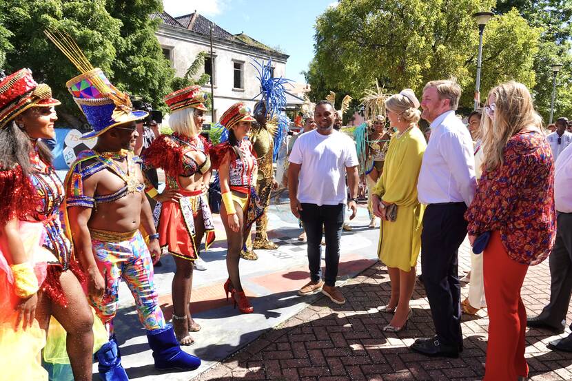 King Willem-Alexander, Queen Máxima and the Princess of Orange speak with dancers during a walk through the Scharloo district in Curacao