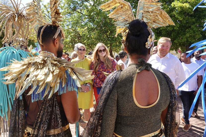 King Willem-Alexander, Queen Máxima and the Princess of Orange speak with dancers during a walk through the Scharloo district in Curacao